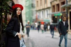 kvinna mode modell promenader på de gata i de stad Centrum bland de folkmassan i en jacka och röd basker och jeans, filmiska franska mode stil Kläder, resa till istanbul foto