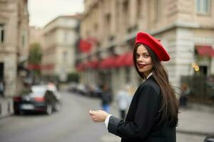 mode kvinna porträtt leende tänder stående på de gata i de stad bakgrund i eleganta kläder med röd mun och röd basker, resa, filmiska Färg, retro årgång stil, urban mode livsstil. foto