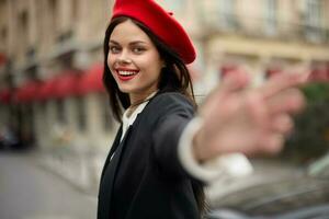 mode kvinna leende med tänder stående på de gata i främre av de stad turist Följ mig eleganta kläder med röd mun och röd basker, resa, filmiska Färg, retro årgång stil, urban mode. foto