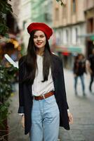 kvinna leende mode modell promenader på de gata i de stad Centrum bland de folkmassan i en jacka och röd basker och jeans, filmiska franska mode stil Kläder, resa till istanbul vår foto