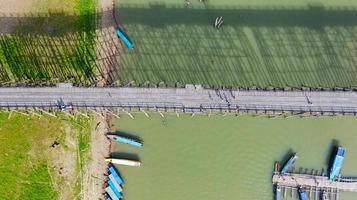 Flygfoto ovanifrån av träbro med turnébåt i Thailand foto