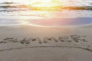 ord sommar på de sand på de hav sandig strand i de solnedgång ljus foto