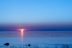 skön röd solnedgång Sol på de hav på de yta av de vatten foto