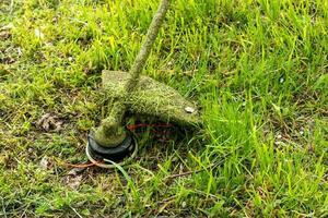närbild av en gräs trimmer under gräsklippning. landskaps begrepp foto