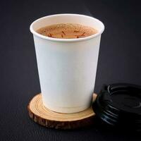 papper kopp av kaffe på en trä- stå på en svart bakgrund. foto