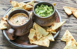 skålar med guacamole och queso med tortillachips foto