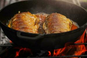 de fisk är friterad i en panorera i olja på en brand. matlagning fisk. foto