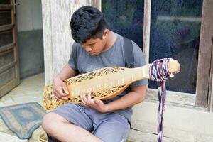 kuaro kalimantan timur, indonesien 21 juni 2023. en man spelar en traditionell kalimantan Dayak musikalisk instrument foto