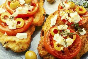 kött schnitzel med ost, oliver och tomat foto