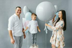 kön avslöja fest. eleganta skön familj med en bebis pop- en ballong till hitta ut de kön av de ofödd barn i de familj foto