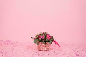 skön bukett av rosa ro och eukalyptus grenar i en gåva korg på en rosa bakgrund med konfetti för födelsedag, hjärtans dag eller mammas dag foto