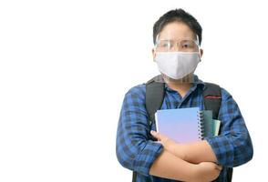 asiatisk pojke studerande ha på sig ansikte skydda och mask bär skola väska isolerat foto