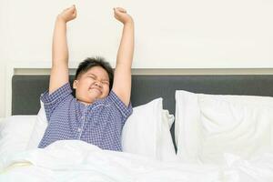 fet fett pojke vaknar upp och stretching på säng i morgon, foto