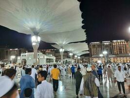 medina, saudi Arabien, Maj 2023 - skön natt tid se av masjid al nabawi, medina. besökare, gårdar utanför de moské, skön lampor och elektronisk paraplyer kan också vara sett. foto