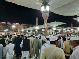 medina, saudi Arabien, Maj 2023 - skön natt tid se av masjid al nabawi, medina. besökare, gårdar utanför de moské, skön lampor och elektronisk paraplyer kan också vara sett. foto