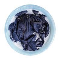 blå jeans med flytande tvättmedel i plastbassängen isolerad på vit bakgrund
