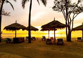 paraply och stol på tropisk strand med soluppgång foto
