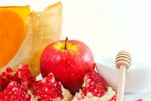 hela granatäpple, granatäpple frön, röd äpple och honung, på vit bakgrund. jewish ny år symboler. foto