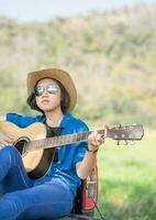 kvinna ha på sig hatt och spelar gitarr på plocka upp lastbil foto