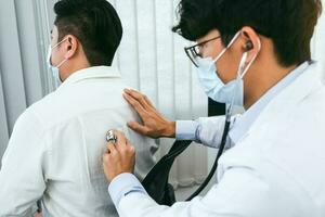 asiatisk läkare använder ett stetoskop, lyssna på patientens hjärtslag. foto