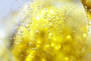 guld olja bubblor stänga upp. cirklar av vatten makro. abstrakt skinande gul bakgrund foto