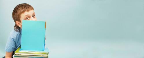 skol är Sammanträde med en stack av böcker och läsning och omslag hans ansikte med en bok isolerat på blå bakgrund foto