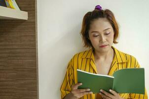 ung kvinna Framställ stående och läsning en bok i de bibliotek foto