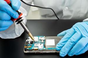 tekniker som reparerar insidan av mobiltelefonen med lödkolv
