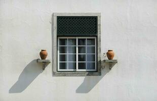 symmetrisk se av en vit vägg med en fönster och två keramisk kastruller foto