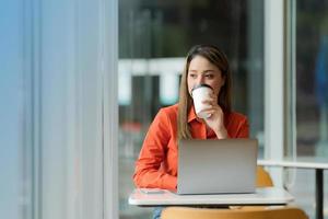 vacker ung kvinna med laptop sitter på ett kafé