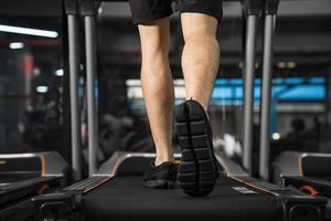 närbild av manliga ben som kör på löpband i gymmet