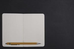 öppen anteckningsbok och penna på svart bakgrund foto