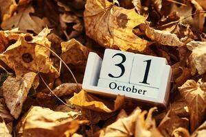 trä- kalender blockera med datum 31 oktober på en faller höst löv bakgrund foto