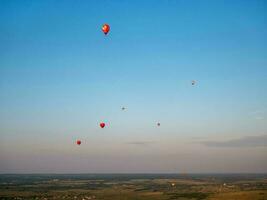 färgrik luft ballong är flygande i fri flyg över de fält. fågelöga se. flerfärgad ballong i de himmel på solnedgång foto