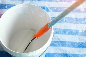 måla vält borsta med hink under målning de vägg. renovering, underhåll och utveckling av Hem eller lägenhet foto