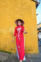 Lycklig kvinna bär ao dai vietnamese klänning och hatt, resande sightseeing på hoi ett gammal stad i central vietnam. landmärke och populär för turist attraktioner. vietnam och sydöst resa begrepp foto