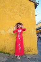 Lycklig kvinna bär ao dai vietnamese klänning och hatt, resande sightseeing på hoi ett gammal stad i central vietnam. landmärke och populär för turist attraktioner. vietnam och sydöst resa begrepp foto