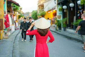 Lycklig kvinna bär ao dai vietnamese klänning, asiatisk resande sightseeing på hoi ett gammal stad i central vietnam. landmärke och populär för turist attraktioner. vietnam och sydöst resa begrepp foto