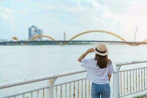 kvinna resande besöker i da nang stad. turist sightseeing de flod se med drake bro. landmärke och populär för turist attraktion. vietnam och sydöst Asien resa begrepp foto