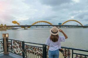 kvinna resande besöker i da nang. turist sightseeing de flod se med drake bro på kärlek låsa bro. landmärke och populär. vietnam och sydöst Asien resa begrepp foto