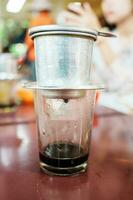 vietnamese kaffe i glas koppar, traditionell metall kaffe tillverkare phin. svart droppa kaffe som känd i vietnam foto