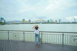 kvinna resande besöker i da nang stad. turist sightseeing de flod se med drake bro. landmärke och populär för turist attraktion. vietnam och sydöst Asien resa begrepp foto