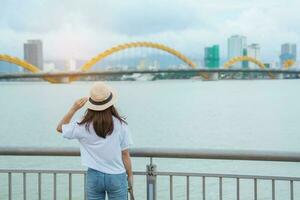 kvinna resande besöker i da nang stad. turist sightseeing de flod se med drake bro. landmärke och populär för turist attraktion. vietnam och sydöst Asien resa begrepp foto