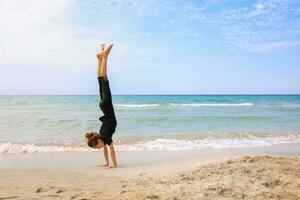 flicka håller på med gymnastik på de strand. foto