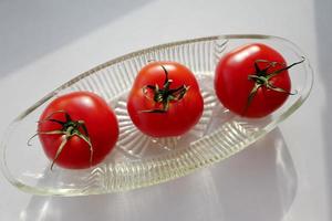 tre tomater i en oval vas foto