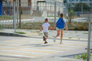 bror och syster springa tvärs över en fotgängare korsning. barn springa längs de väg till dagis och skola.zebra trafik promenad sätt i de stad. begrepp fotgängare godkänd en övergångsställe foto