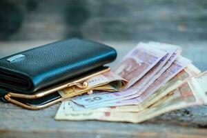 läder plånbok, med ukrainska pengar på en trä- tabell - 50 och 100 ukrainska hryvnias. kontanter anteckningar. fattigdom, inflation. foto