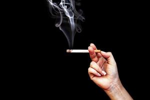 bild av cigarett i handen med rök foto