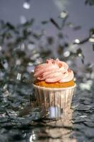 en muffin med en rosa keps står bland de flygande silver- konfetti. foto