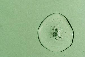 en släppa av transparent kosmetisk gel på en grön bakgrund. foto